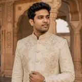 AI illustration of an Indian man in an ivory embroidered formal jacket beneath a sandstone palace arch. — AI style illustration